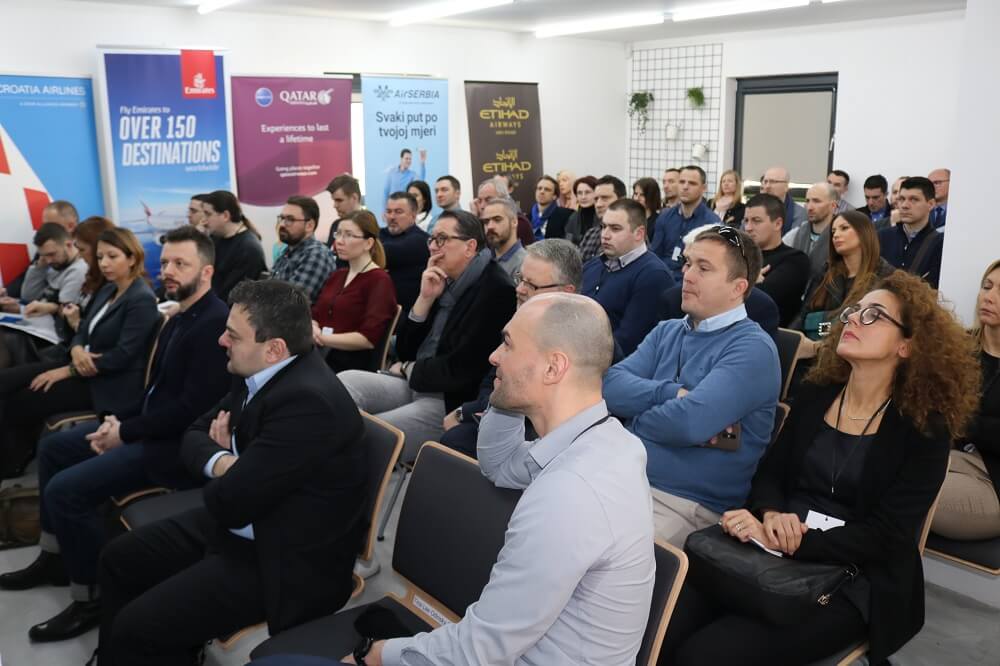 Puna dvorana sjedi i sluša, iza njih panoi zrakoplovnih kompanija